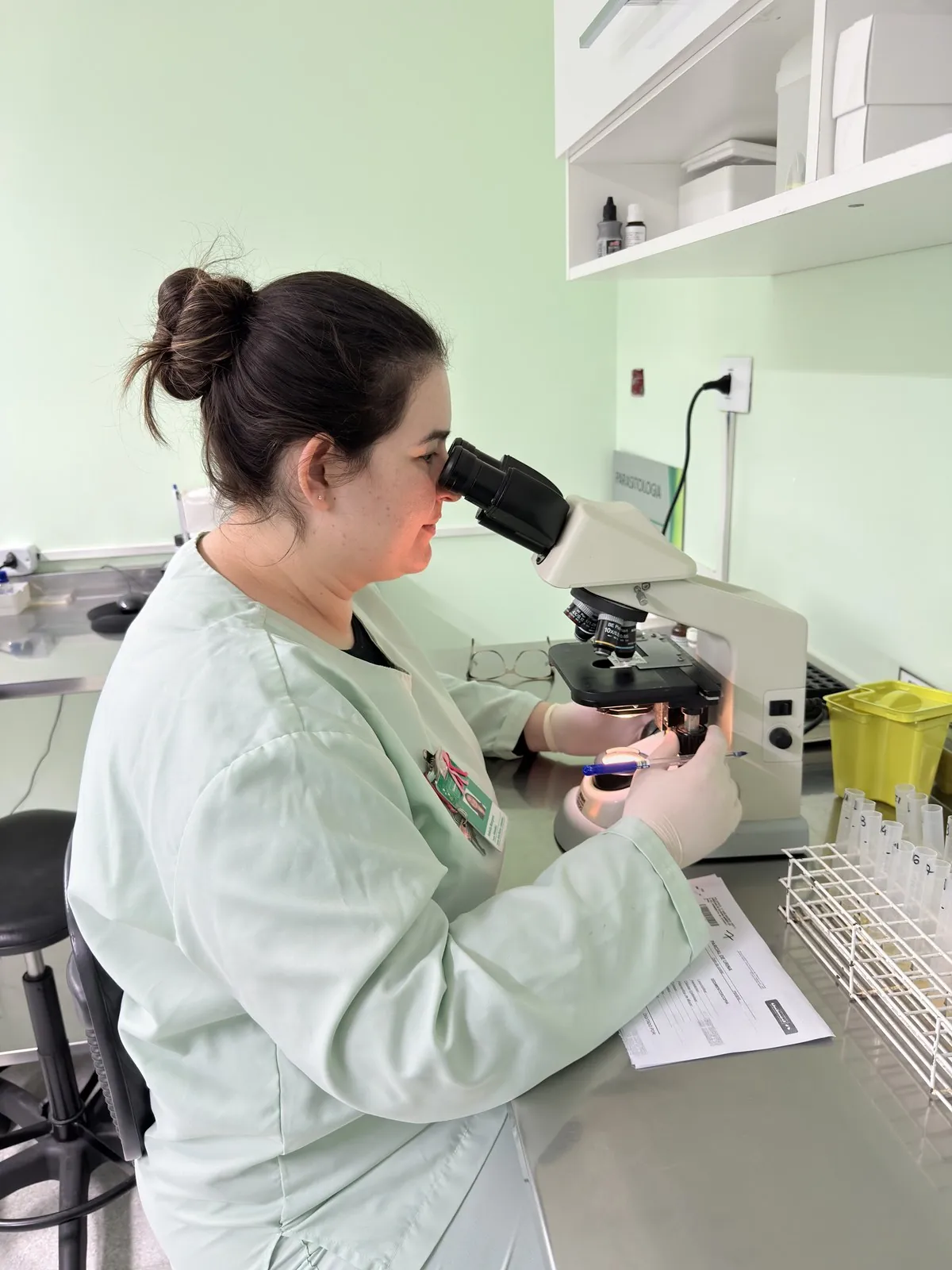 Biomédica analisando amostra no microscópio
